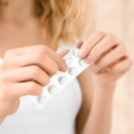 Mulher segurando uma cartela de anticoncepcional